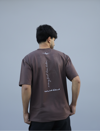 Man wearing a brown t-shirt with text on the back, standing against a plain background