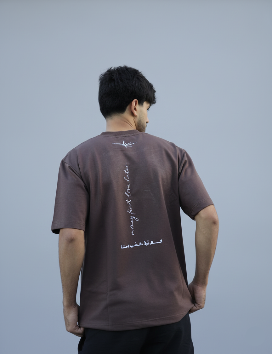 Man wearing a brown t-shirt with text on the back, standing against a plain background