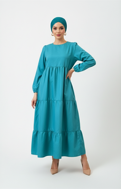 Woman wearing a teal dress and headscarf on a white background