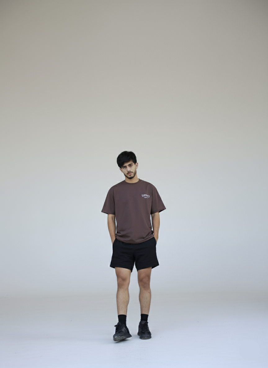 Person wearing a brown t-shirt and black shorts on a white background