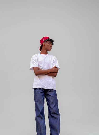 Person wearing a white t-shirt, blue jeans, and a red cap on a gray background