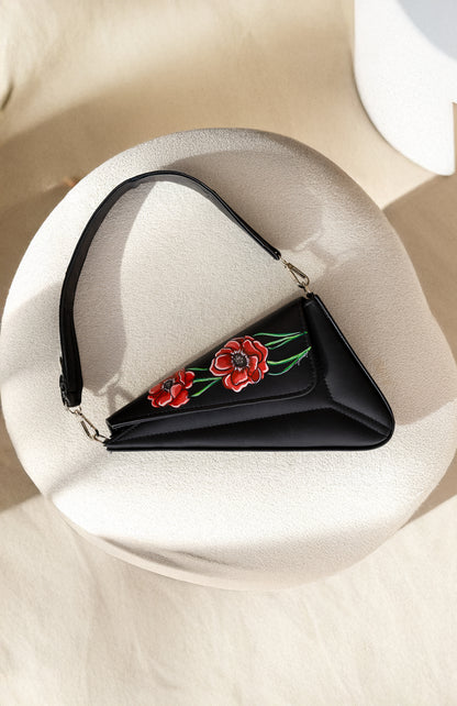 Black handbag with floral embroidery on a white surface