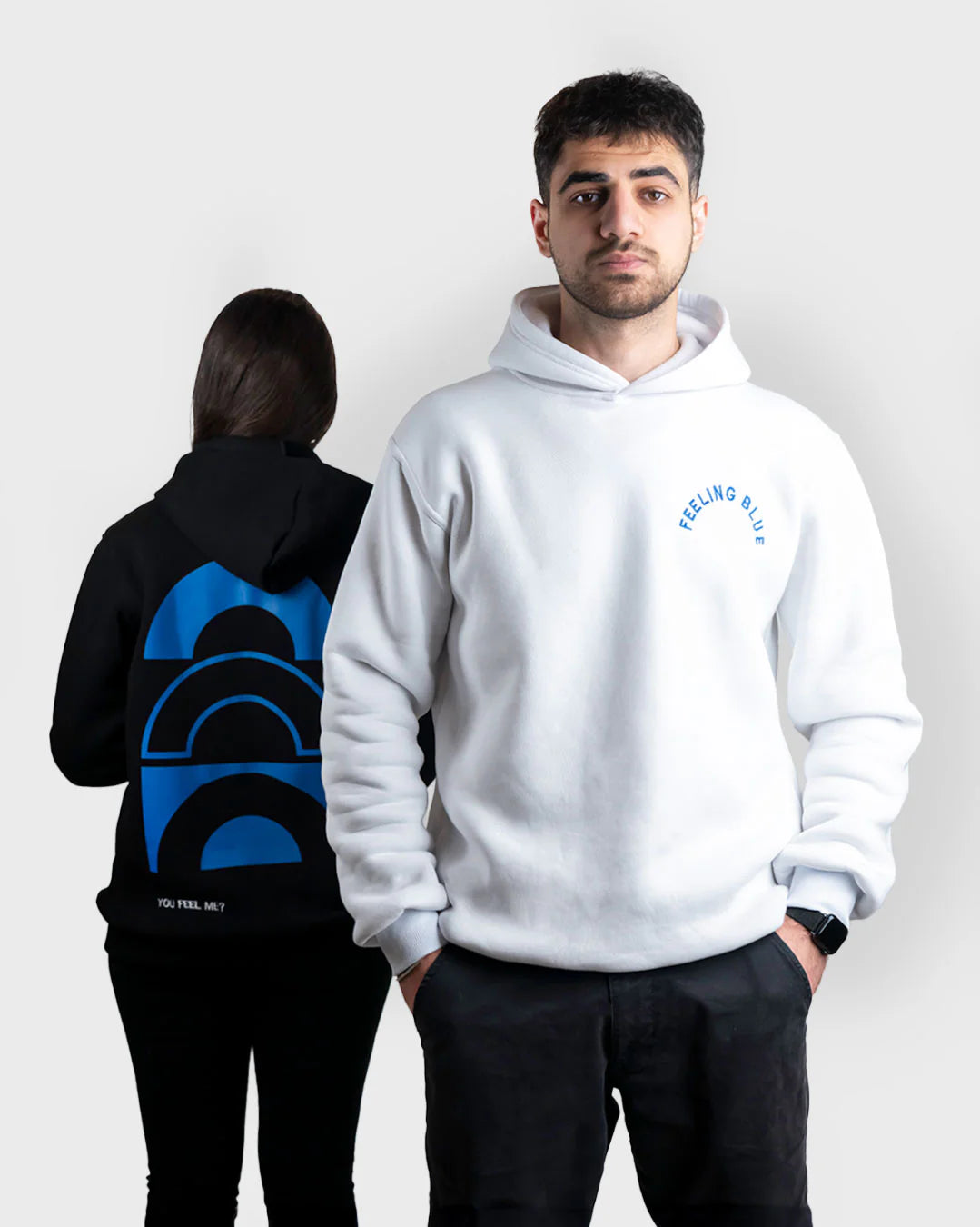 Two people wearing hoodies with visible branding on a plain background