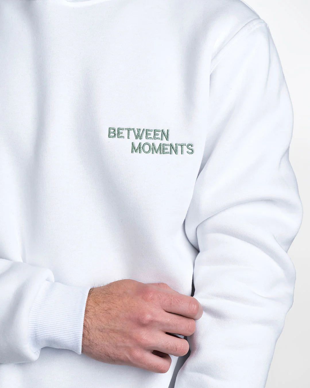 White sweatshirt with 'BETWEEN MOMENTS' text on a plain background
