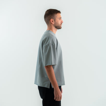 Man wearing a light gray t-shirt against a white background