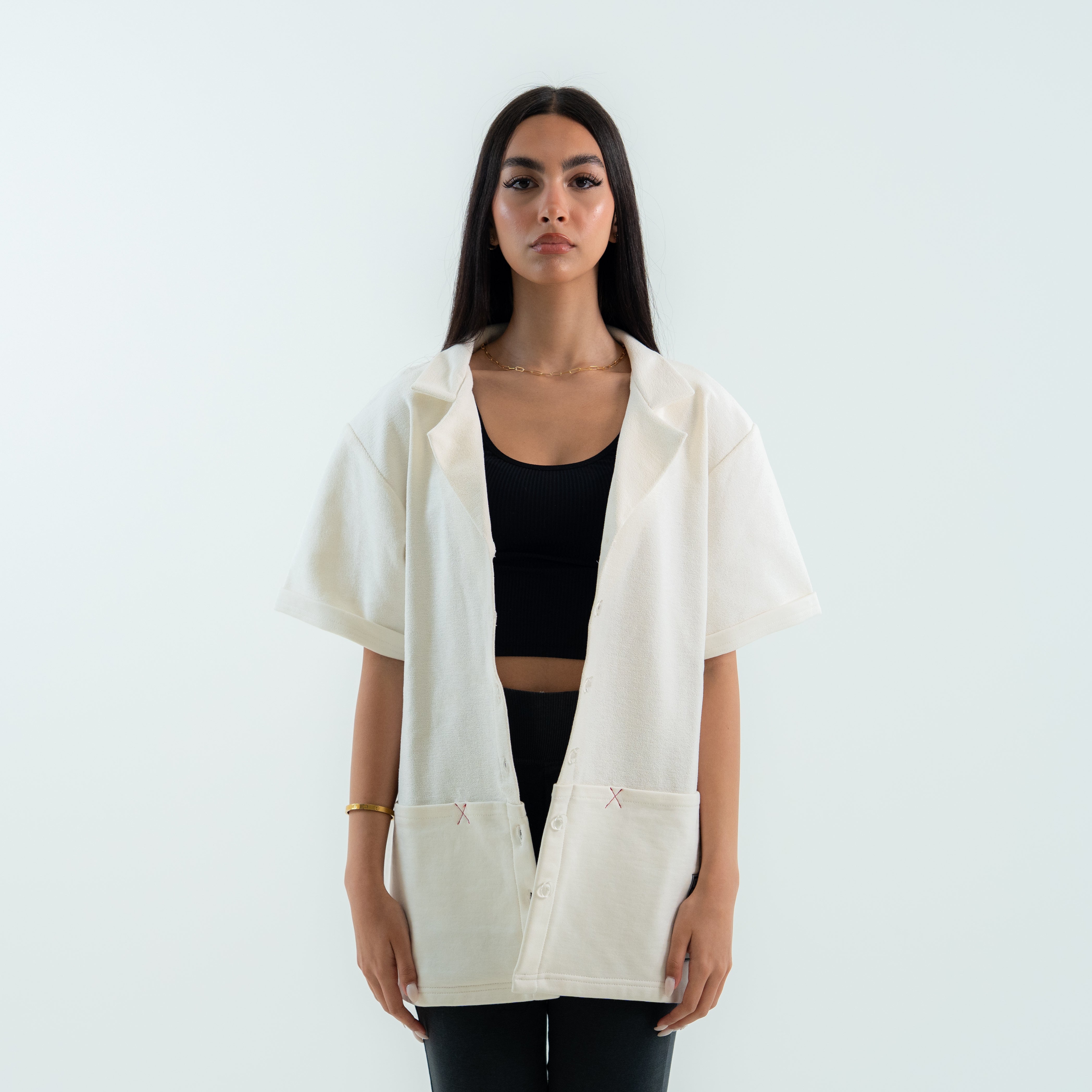 Woman wearing a white shirt over a black top on a light gray background