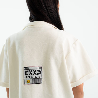 Person wearing a white polo shirt with a label on the back