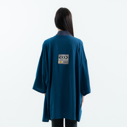 Person wearing a teal coat with a label on the back against a white background