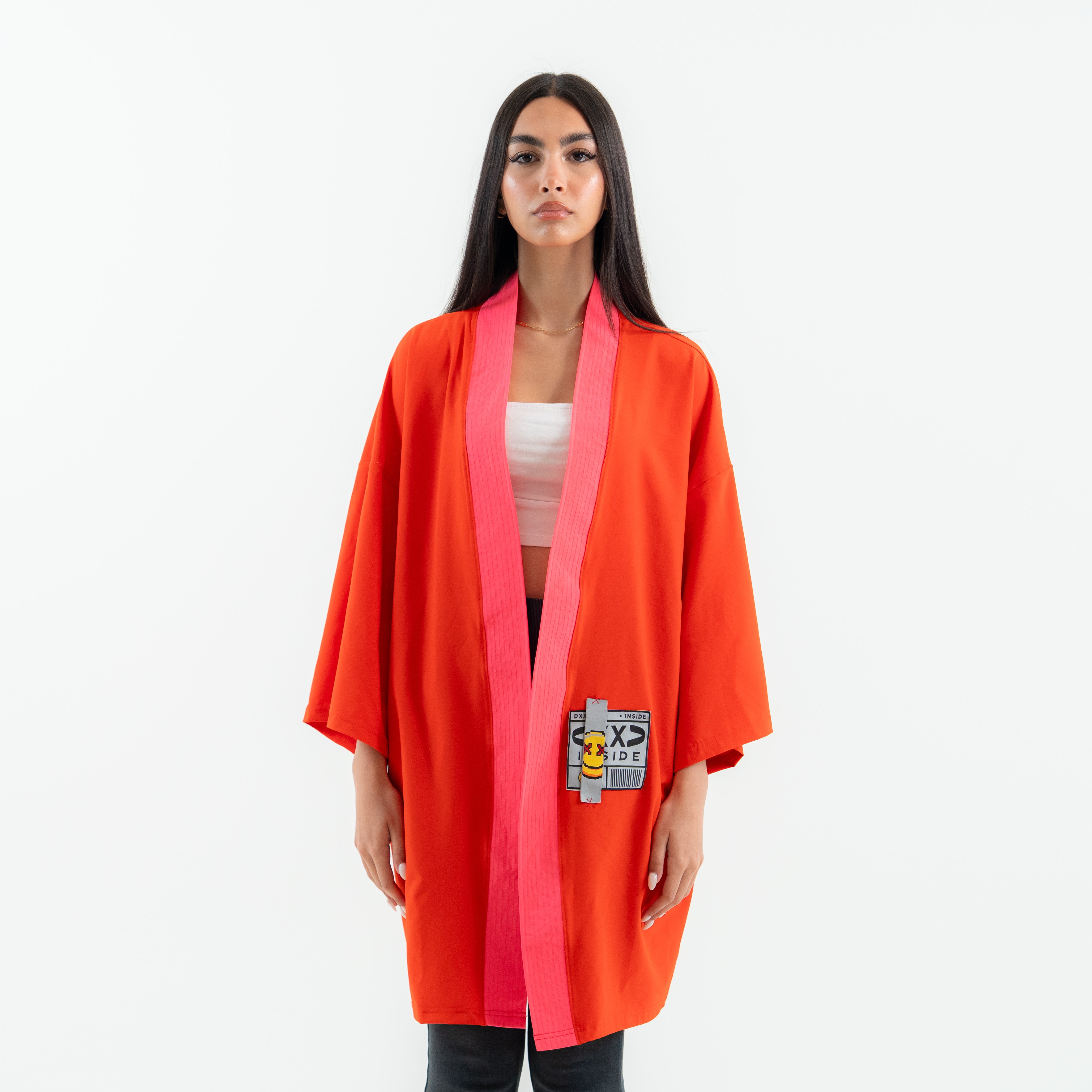 Woman wearing a bright orange kimono-style garment on a white background
