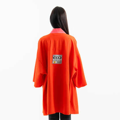 Person wearing an orange lab coat with a label on the back against a white background