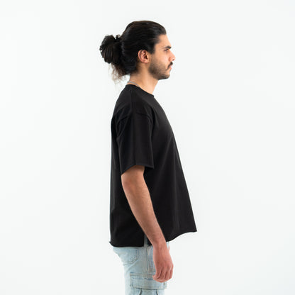 Man wearing a black t-shirt and light blue jeans on a white background