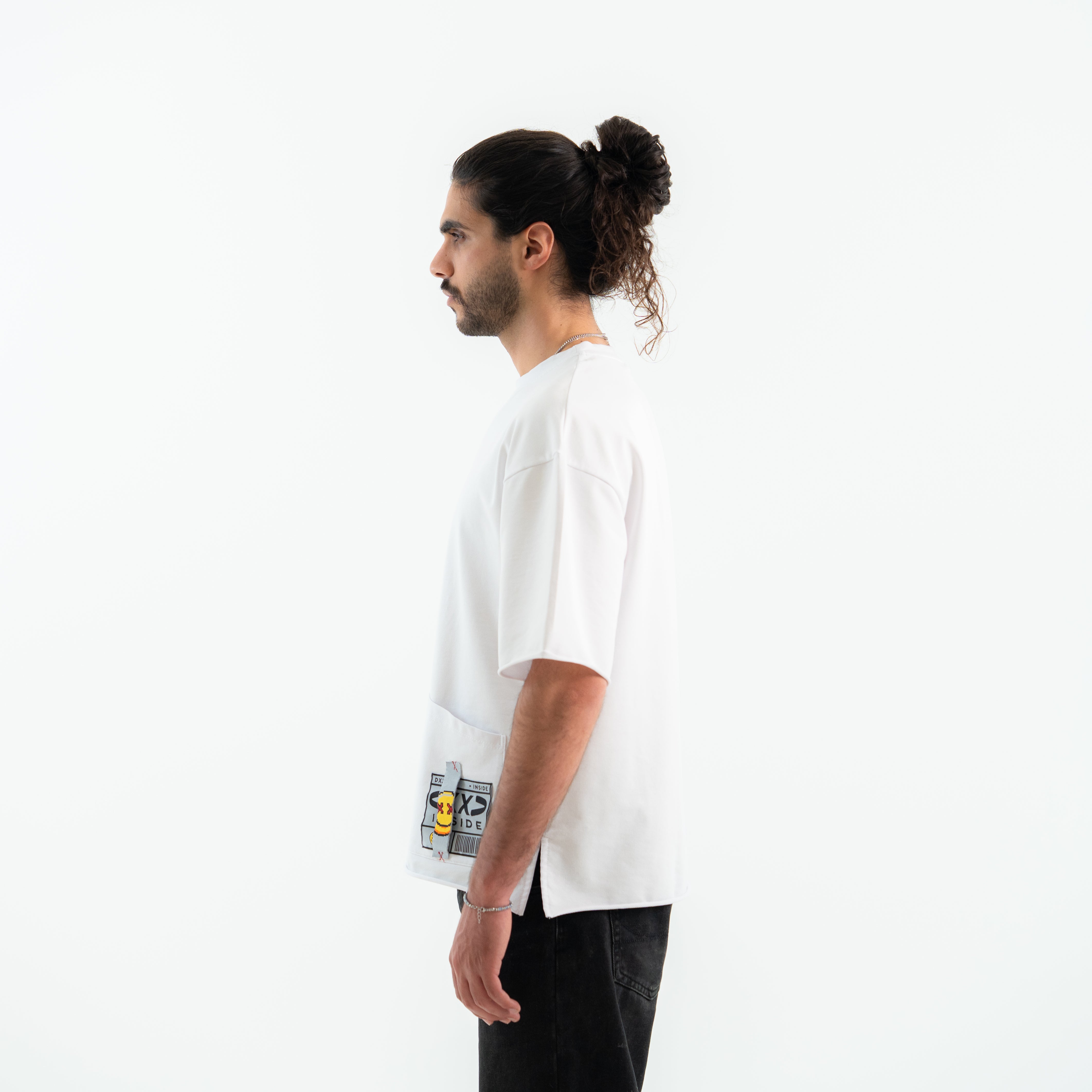 Person wearing a white t-shirt with a graphic design on a plain background