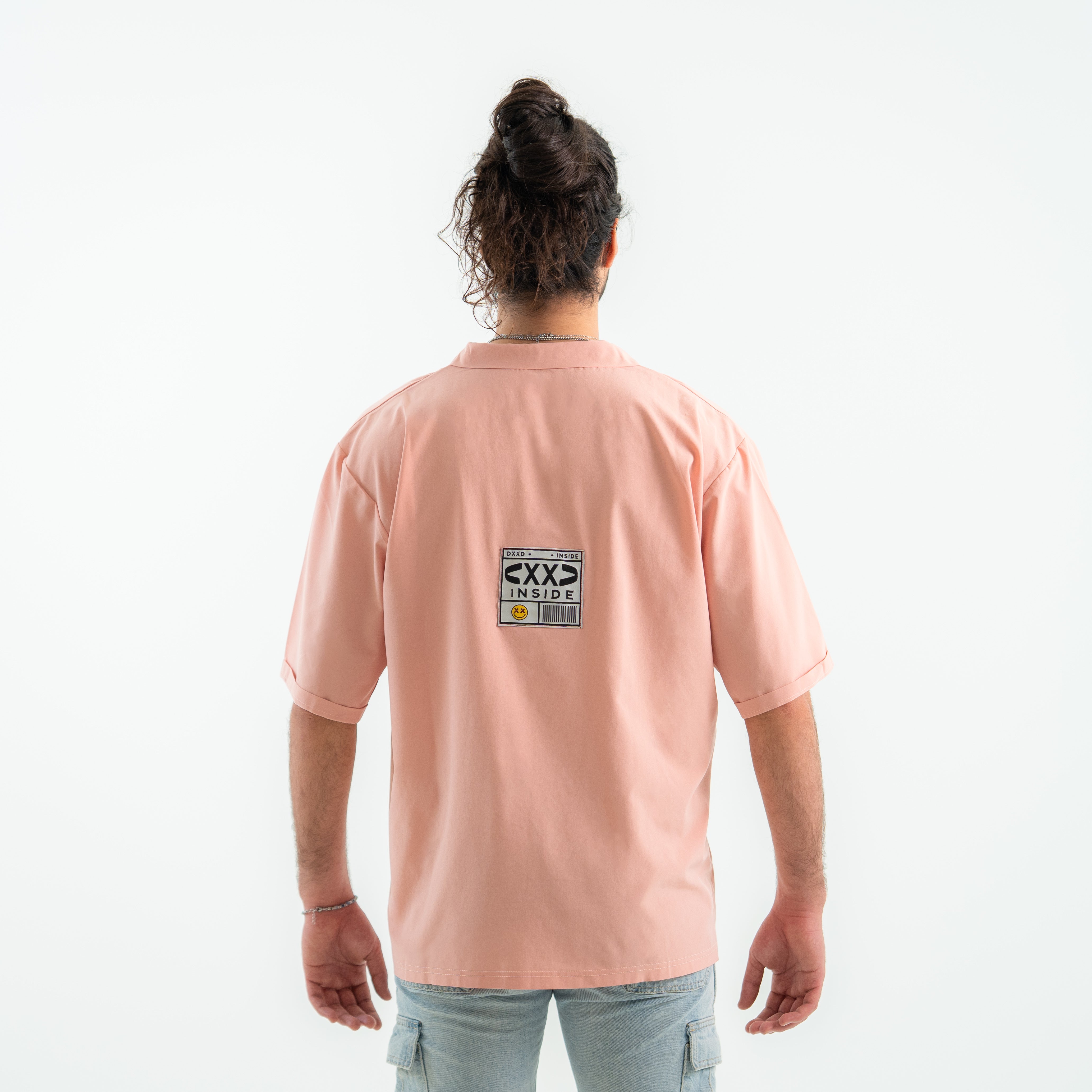 Person wearing a pink t-shirt with a graphic on the back against a white background