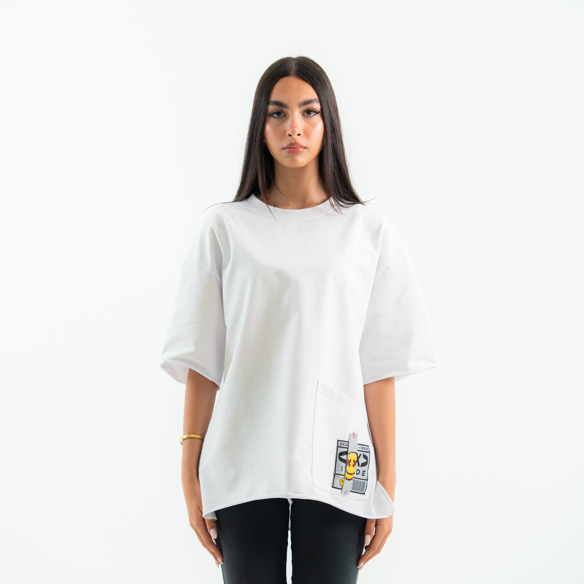 Person wearing a white oversized t-shirt with graphic designs on a plain background