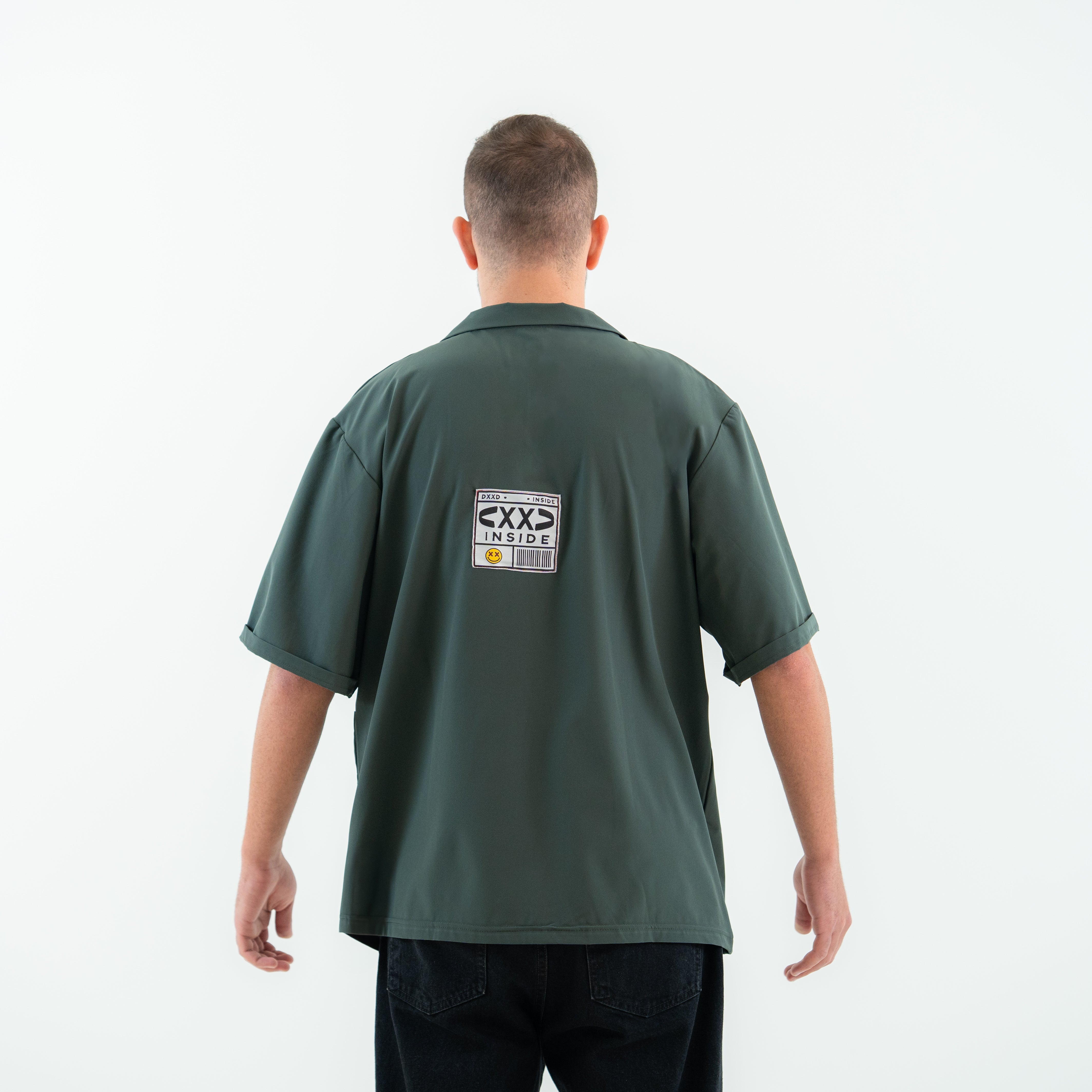 Man wearing a green polo shirt with a logo on the back against a white background