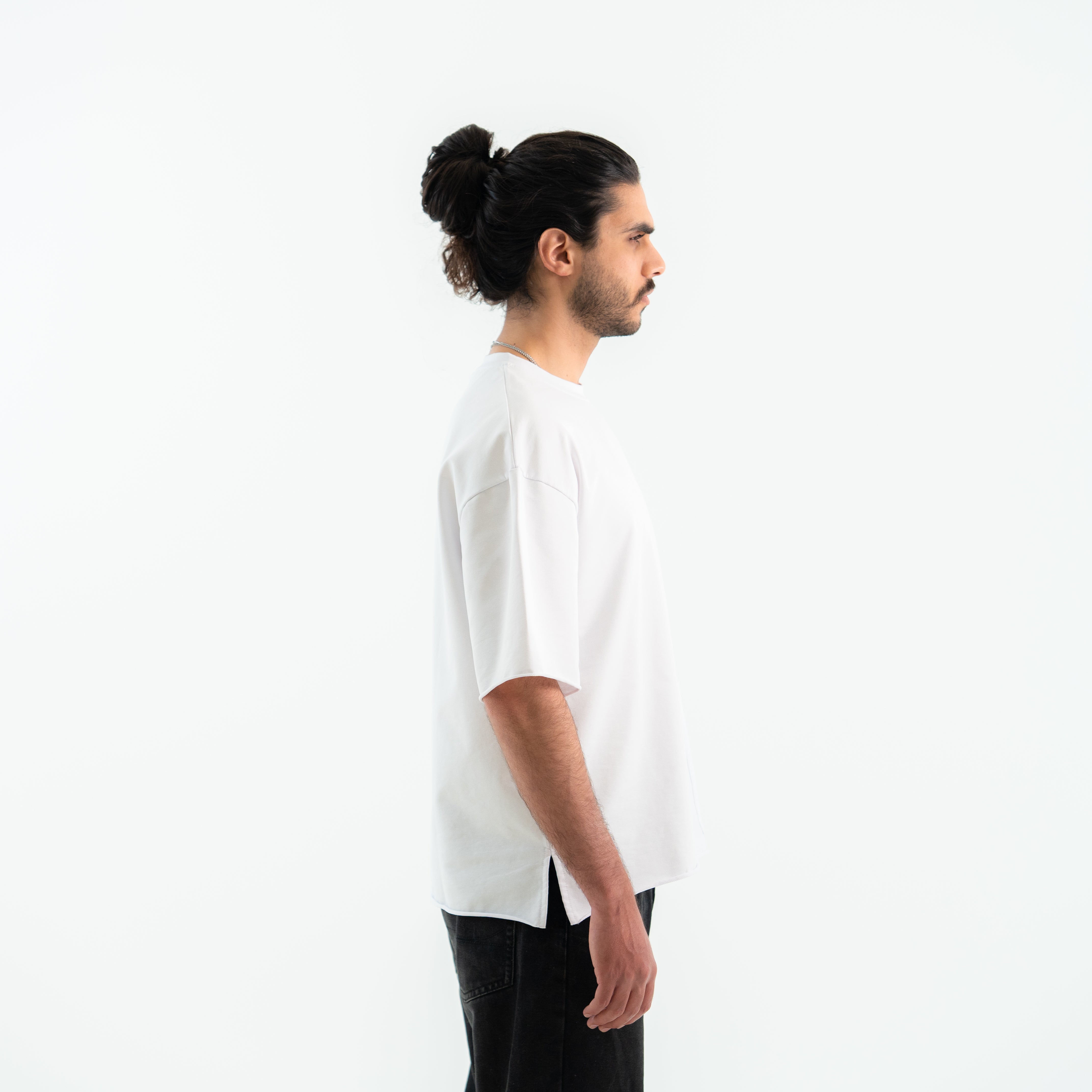 Man wearing a white t-shirt and black pants on a white background