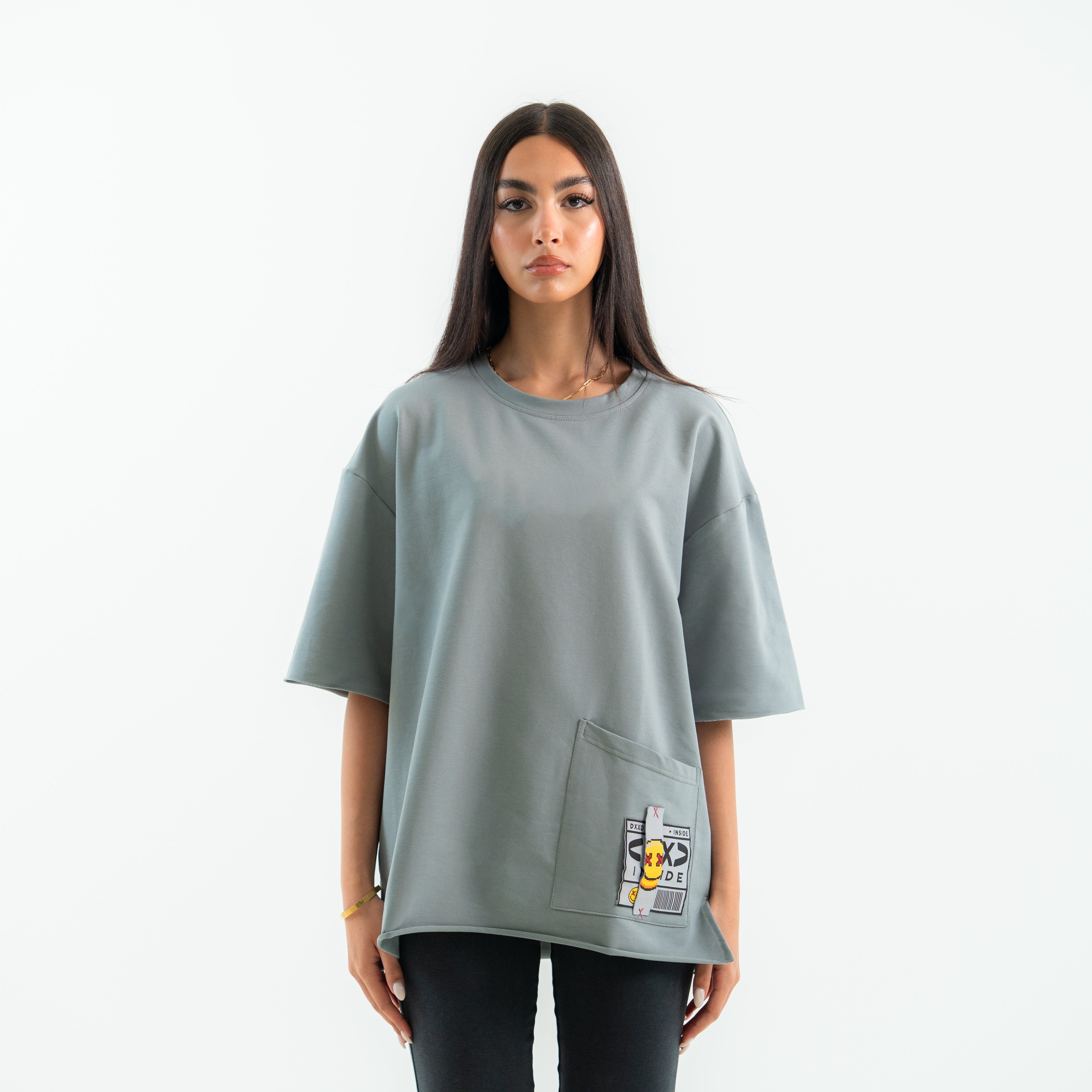 Woman wearing a light gray oversized t-shirt with a graphic on the chest against a white background