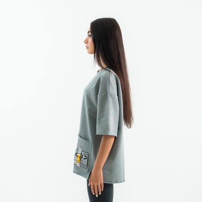 Woman wearing a light gray oversized shirt with patches on a white background