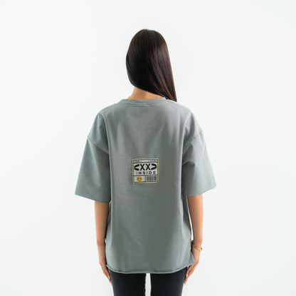 Person wearing a gray t-shirt with a logo on the back against a white background