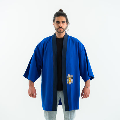 Man wearing a blue martial arts robe with a logo on a white background