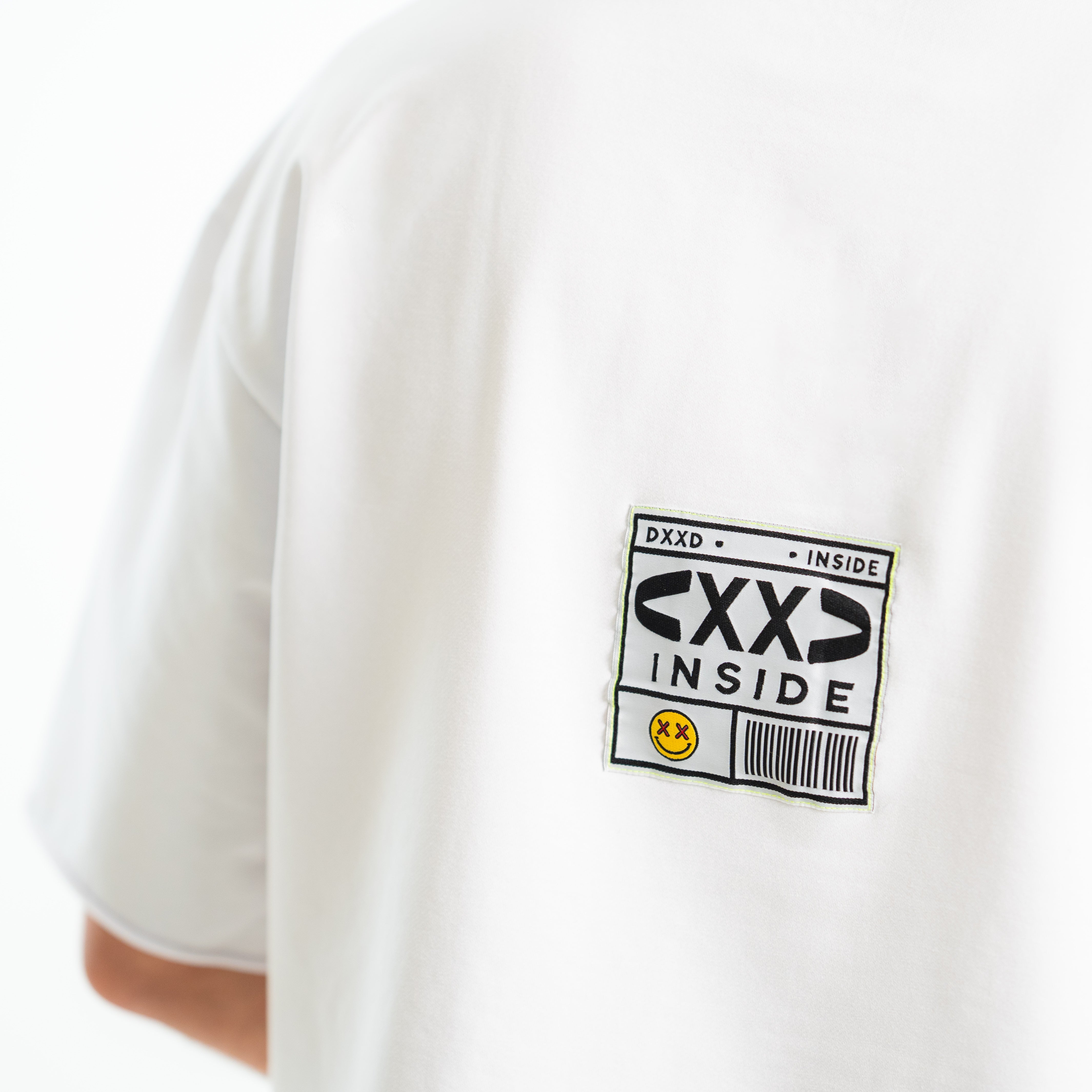 White t-shirt with a black and yellow label on the sleeve