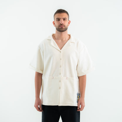 Man wearing a cream-colored shirt with short sleeves on a white background