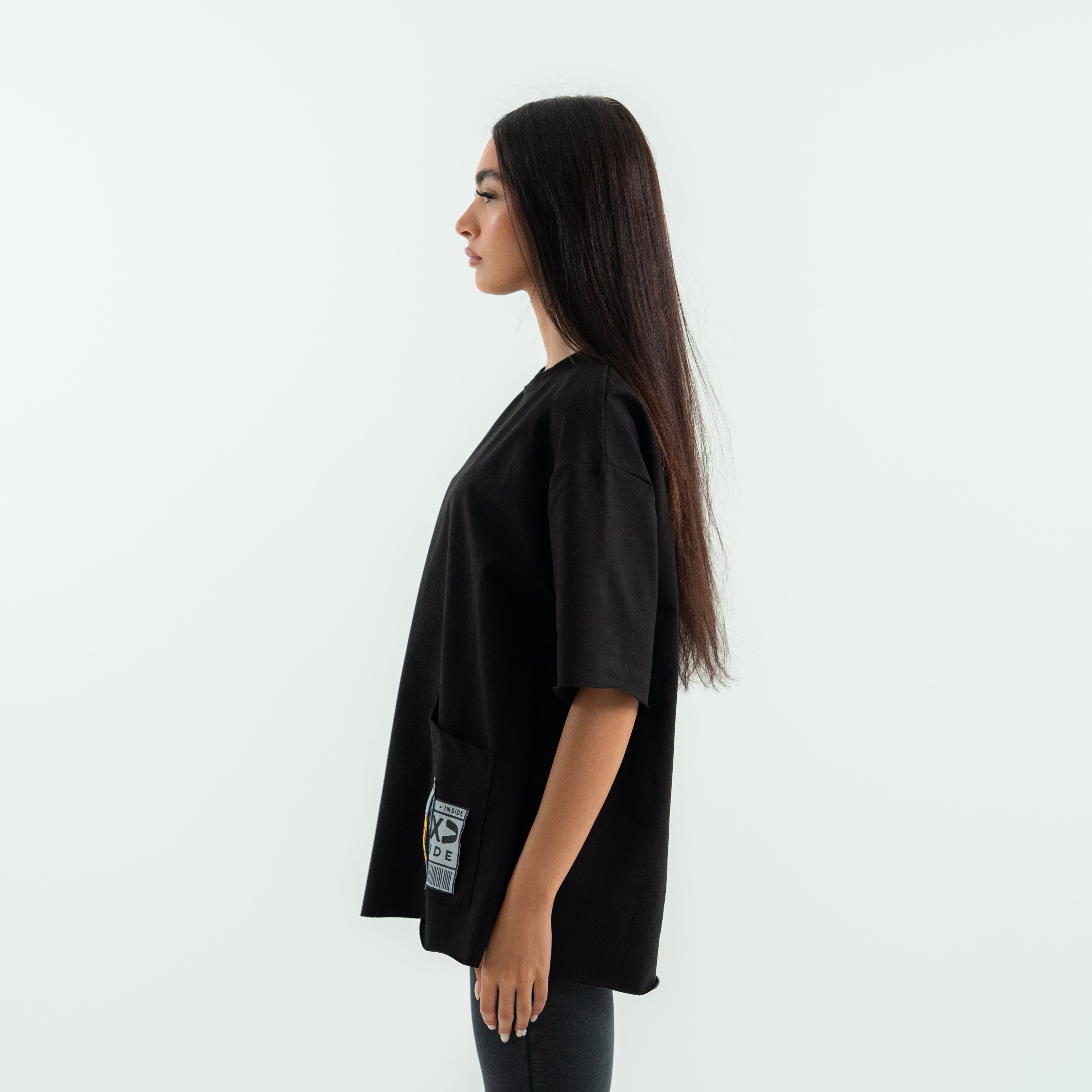 Woman wearing a black oversized t-shirt with a small logo on a white background