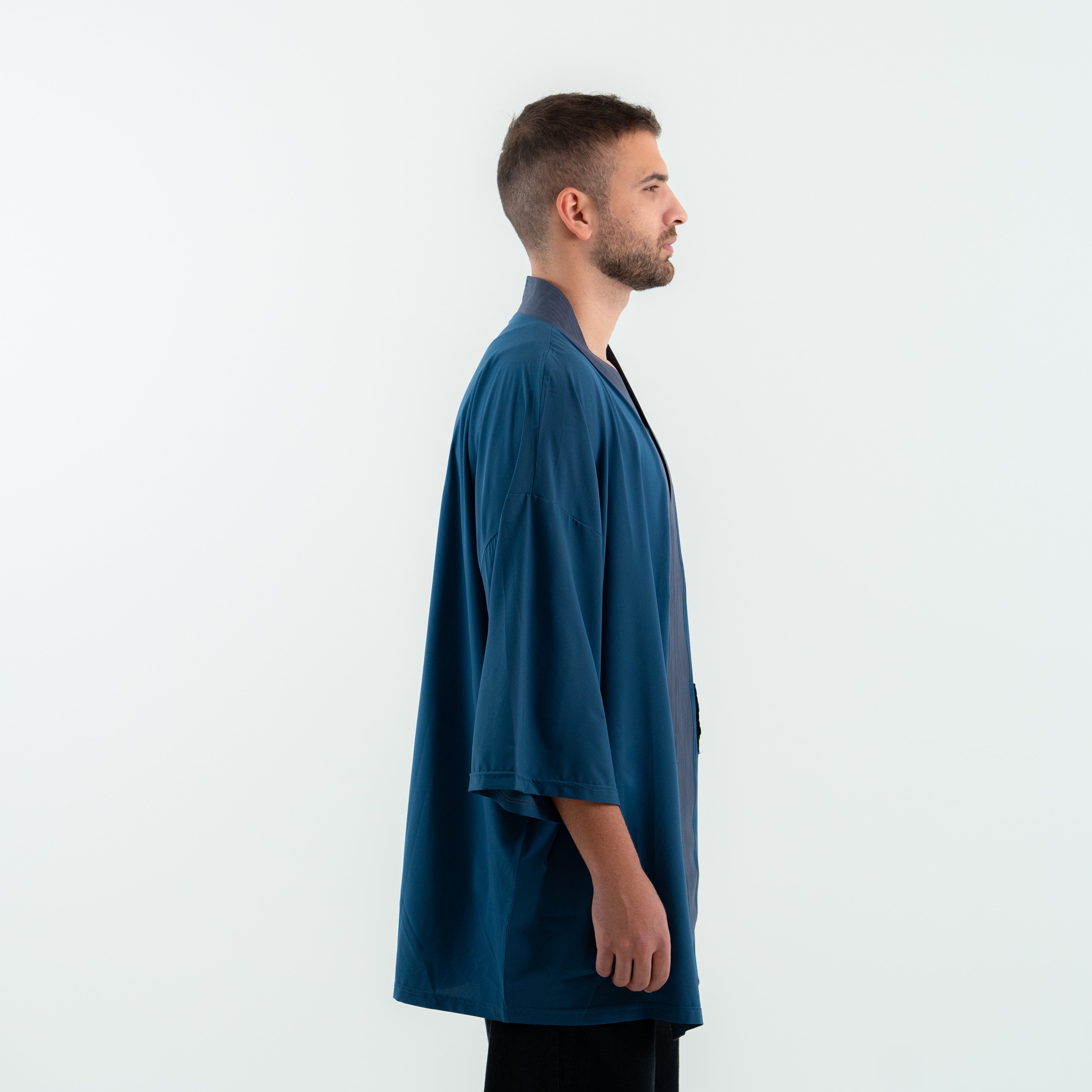 Man wearing a teal kimono-style garment against a white background