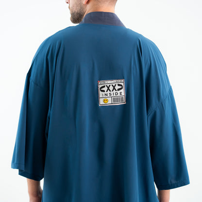 Person wearing a blue shirt with a label on the back against a white background