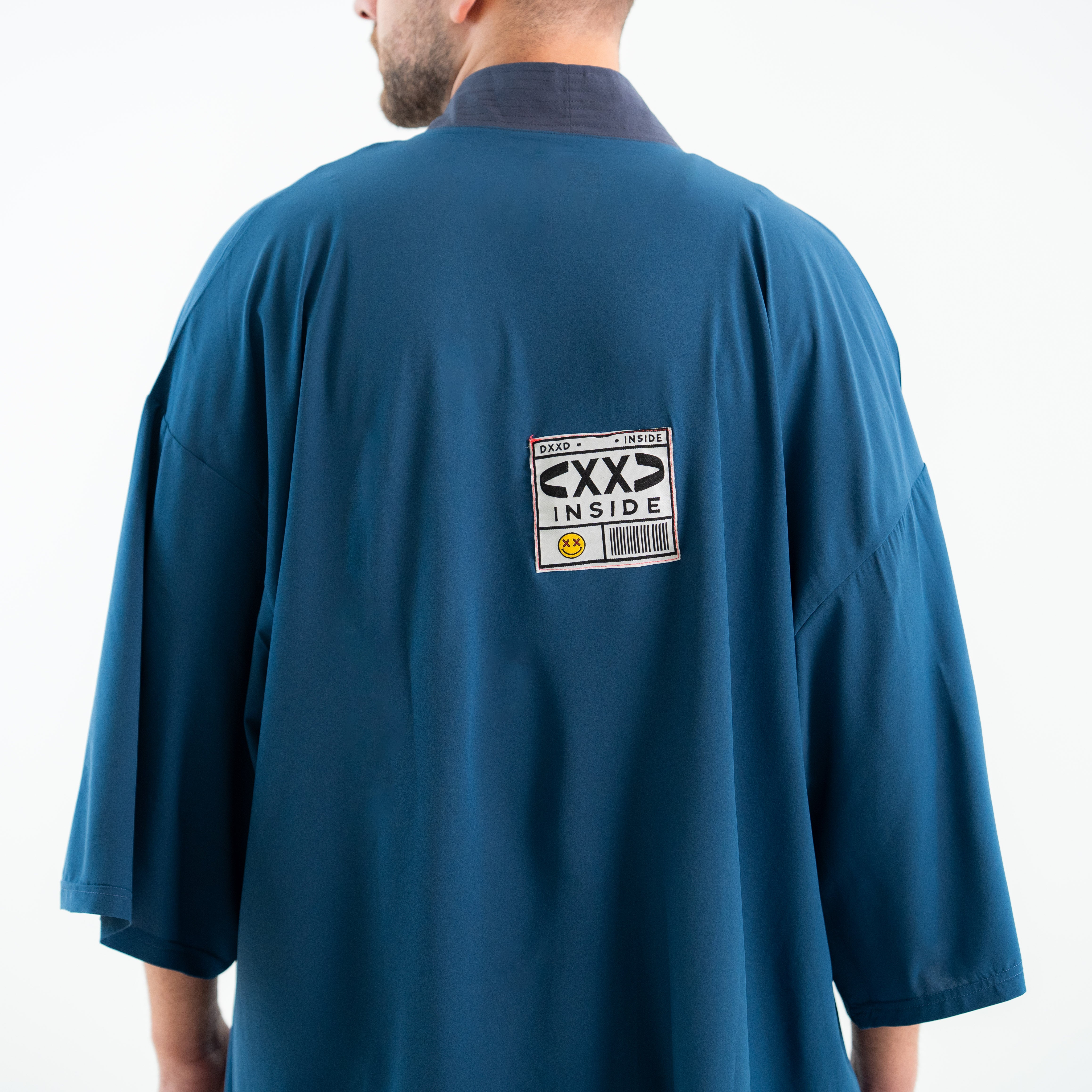 Person wearing a blue shirt with a label on the back against a white background