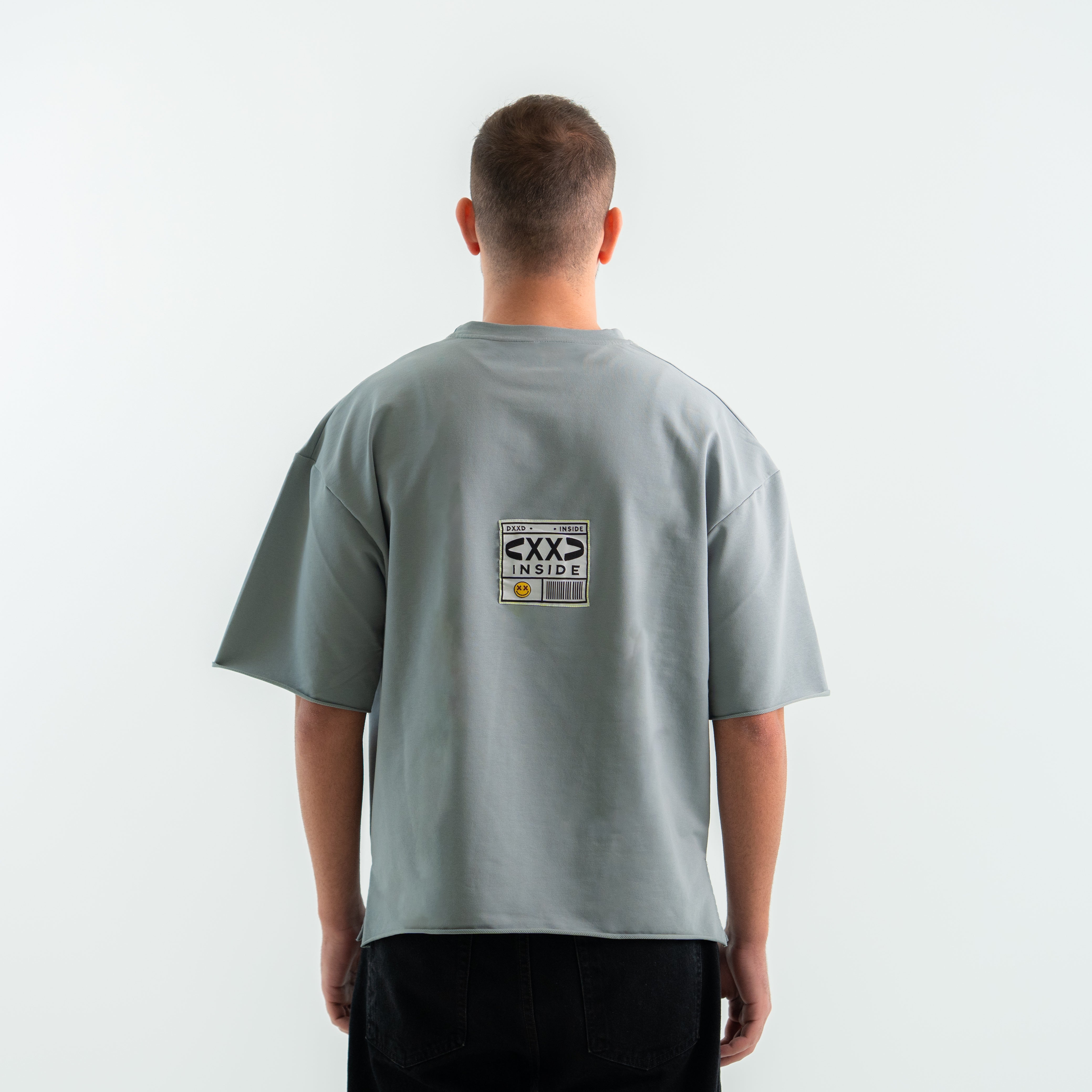 Person wearing a gray t-shirt with a logo on the back against a white background