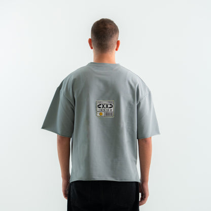 Person wearing a gray t-shirt with a logo on the back against a white background