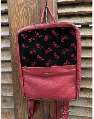 Red backpack with black floral pattern on a wooden background