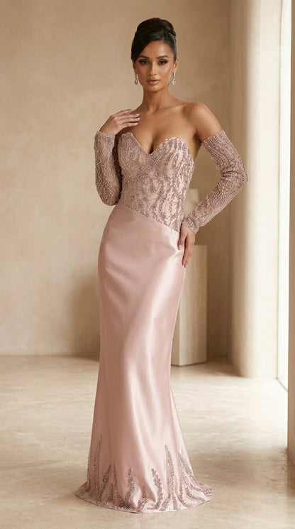 Woman wearing a pink evening gown with long sleeves in a softly lit room.