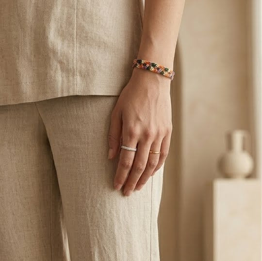 Person wearing a bracelet and ring with a neutral background