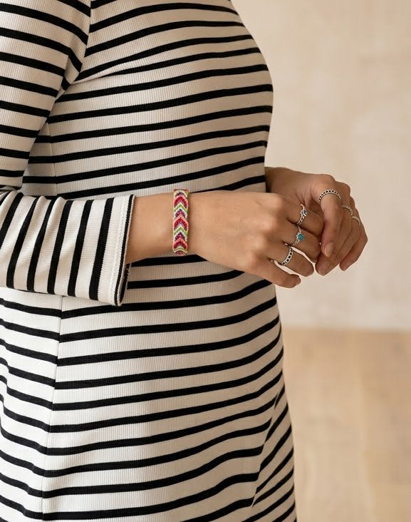 Person wearing a striped dress with visible jewelry on a neutral background