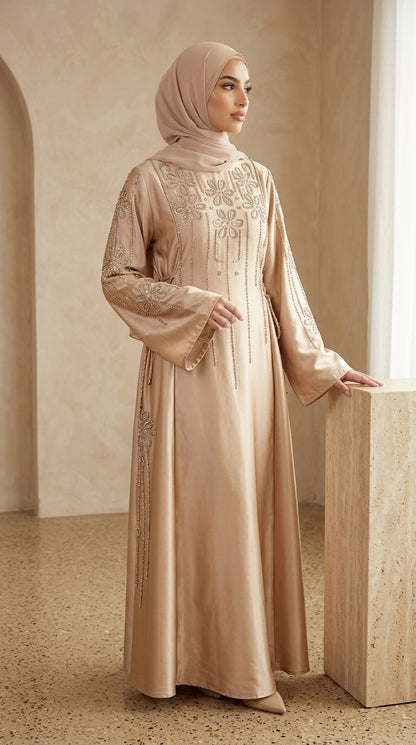 Woman wearing a beige embroidered abaya in an elegant interior setting