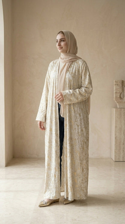 Woman wearing a beige abaya and hijab in a minimalistic setting