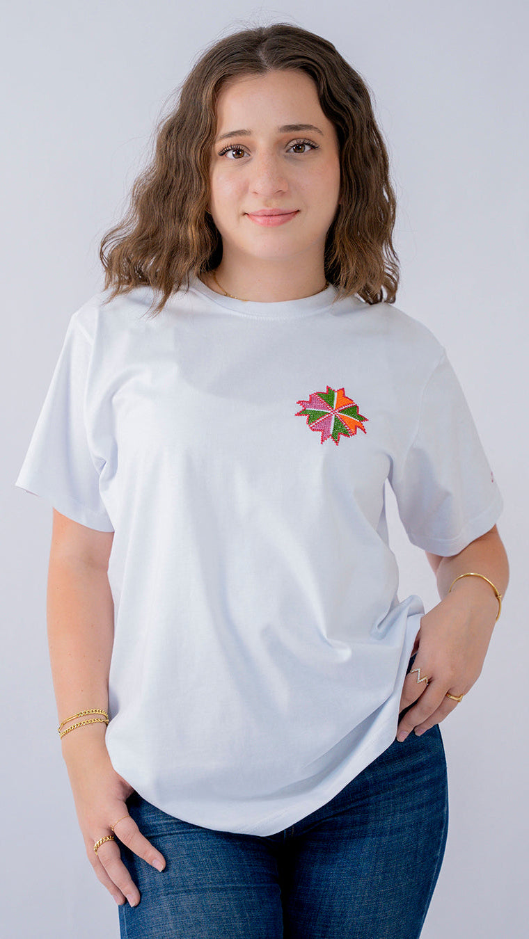 Woman wearing a white t-shirt with a colorful flower design on a plain background