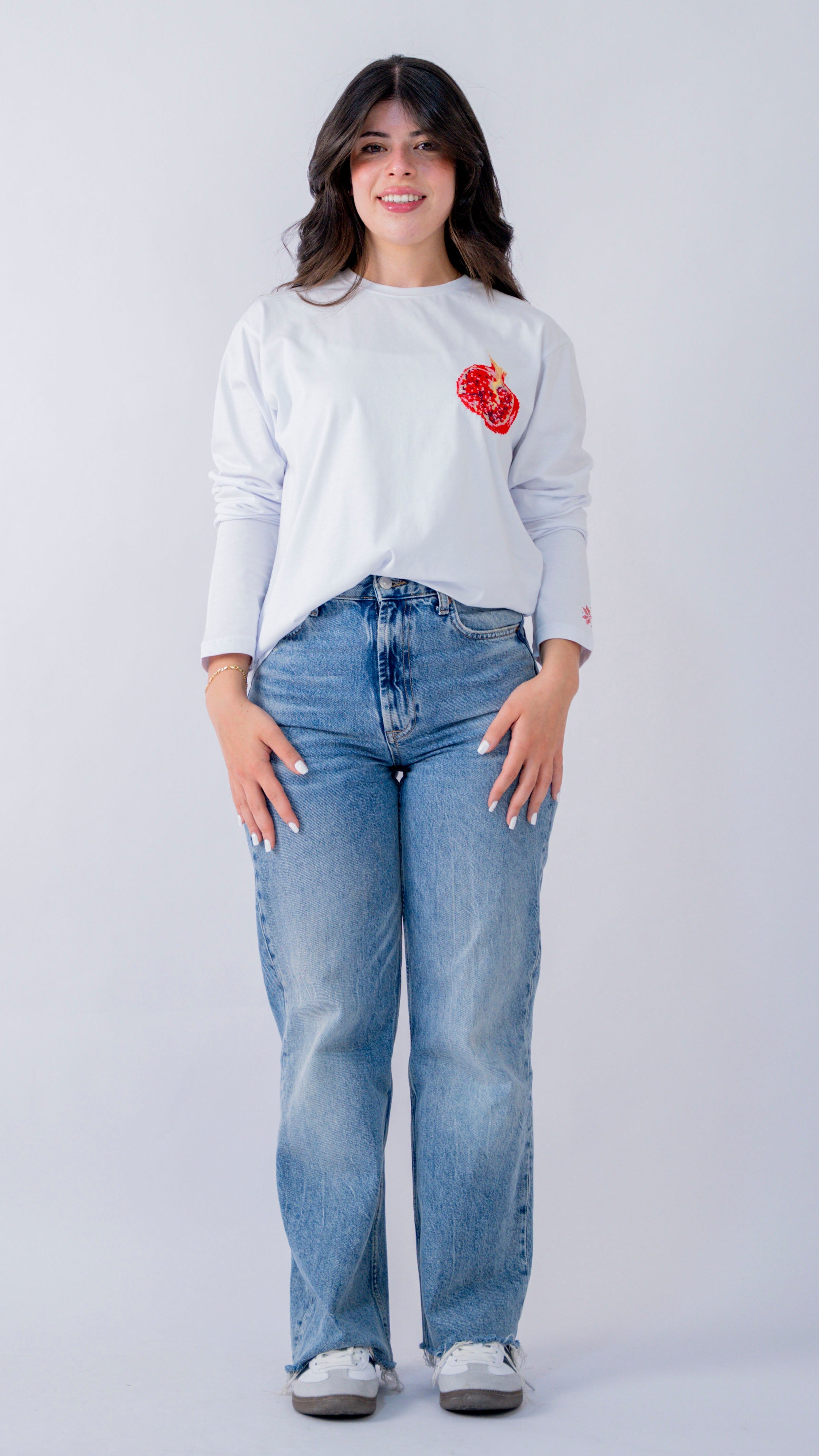 Woman wearing a white sweater with a red heart design and blue jeans on a white background