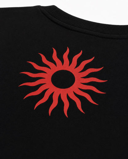 Close-up of a black crewneck sweatshirt featuring a bold red sunburst graphic printed on the chest.