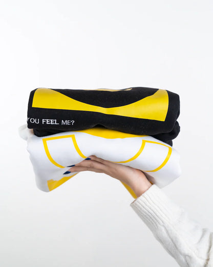 Person holding a black and yellow pillow with text on a white background