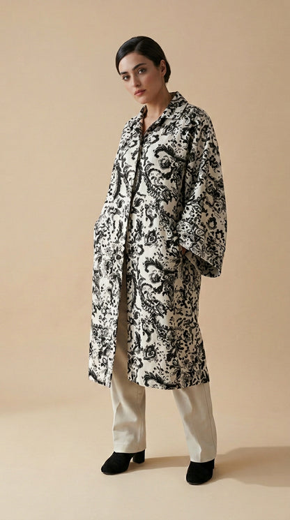 Woman wearing a black and white patterned coat on a beige background