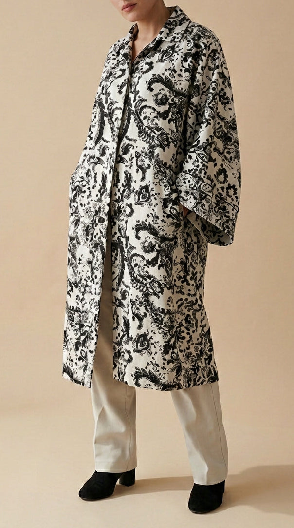 Woman wearing a black and white patterned coat on a beige background