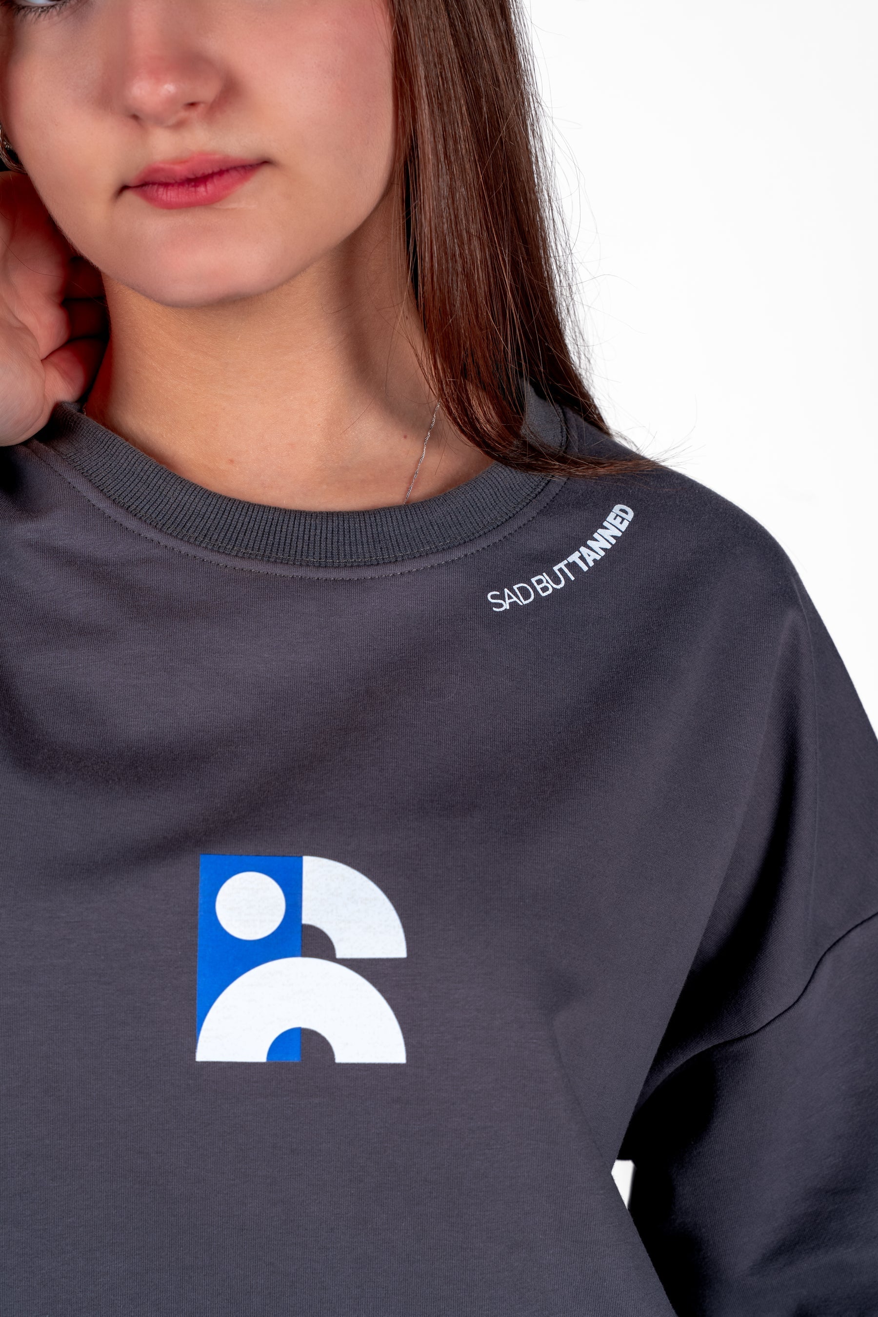 Person wearing a dark gray sweatshirt with a logo and text on a white background