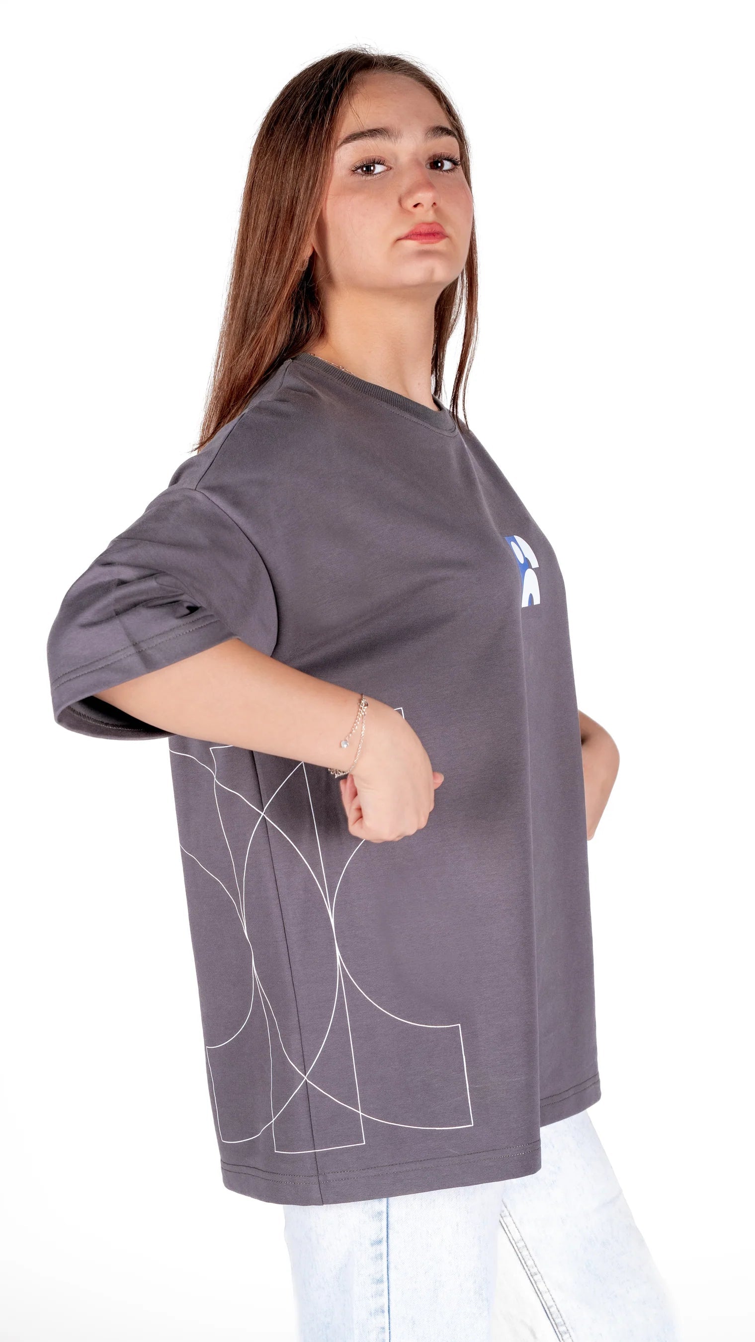 Person wearing a gray oversized t-shirt with a logo on a white background