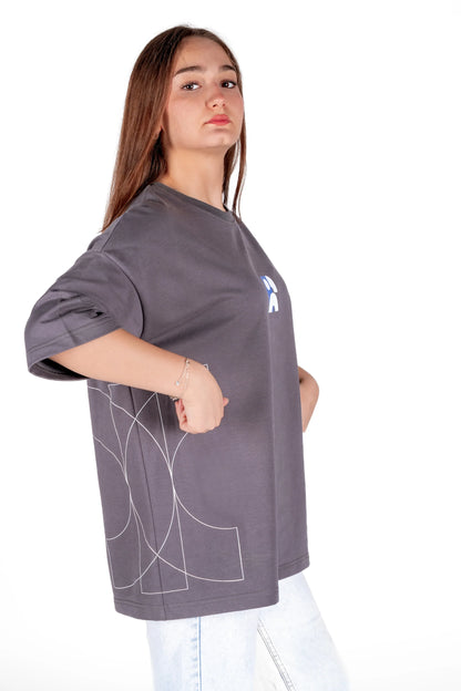 Person wearing a gray oversized t-shirt with a logo on a white background