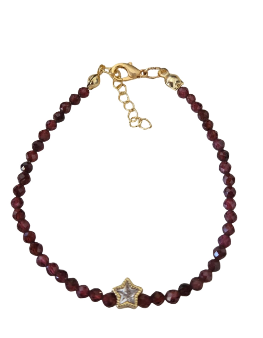 Bracelet with red beads and a gold star-shaped clasp on a white background