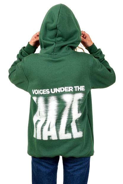 Green hoodie with 'Voices Under the Haze' text on the back, worn by a person.