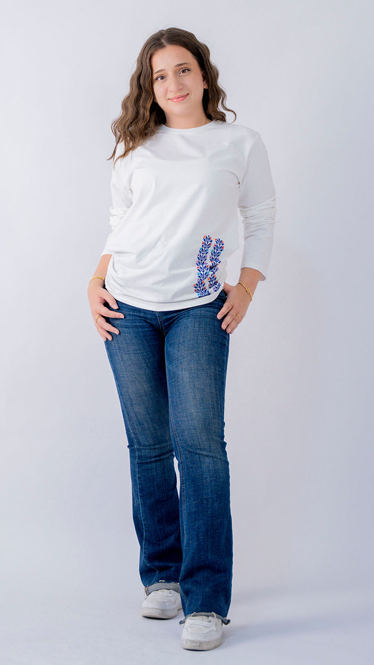 Woman wearing a white sweatshirt with a colorful design and blue jeans on a white background